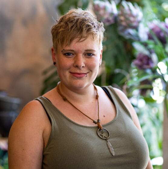 Eine Frau in einem grünen Kleid steht vor einer Pflanze. {{brizy_dc_image_alt imageSrc=