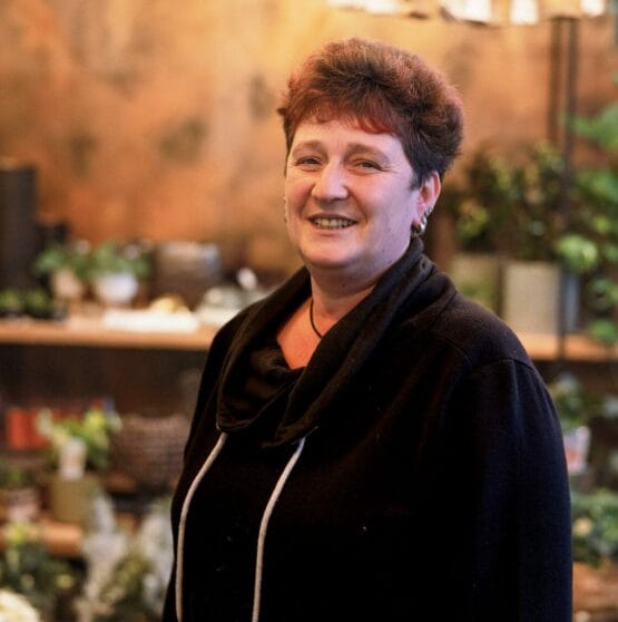 Eine Frau steht vor einem Blumenladen. {{brizy_dc_image_alt imageSrc=